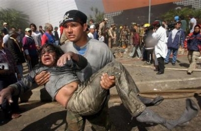 A child is helped out of the Ycua Bolanos supermarket in Asuncion, Paraguay on Sunday, Aug. 1, 2004. The fire broke out at the Ycua Bolanos supermarket while it was crowded with Sunday midday shoppers. (Photo: AP / Jorge Saenz)