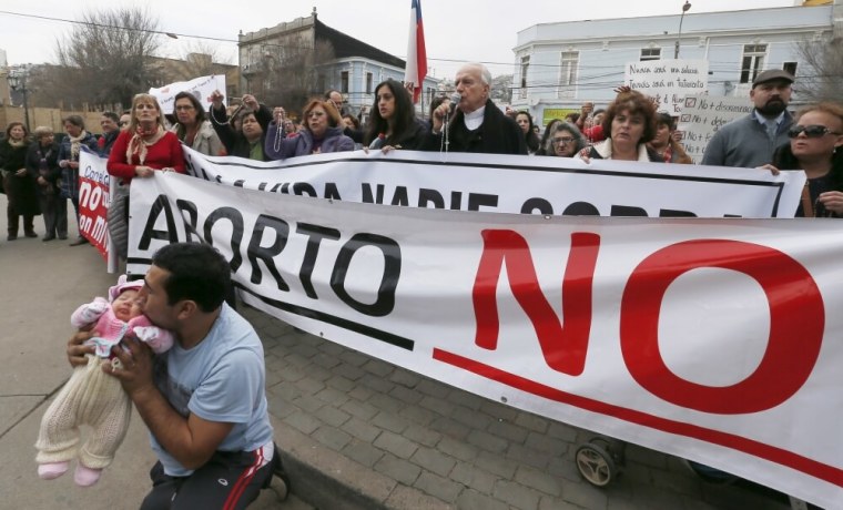 A demonstrator kisses his child as archbishop Gonzalo Duarte prays outside Congress during a rally against the draft law of the Chilean government which seeks to legalize abortion, in Valparaiso, August 4, 2015. President Michelle Bachelet's push to relax strict abortion laws in socially conservative Chile has created a rift inside her ruling coalition and key elements of the reform are likely to be scratched. Bachelet's proposals would allow an abortion if a mother's life is in danger, if a baby is deemed to have