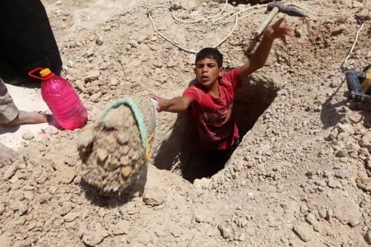 A boy digs a grave at the Wadi al-Salam cemetery, Arabic for "Peace Valley", in Najaf, south of Baghdad, Iraq July 27, 2016.