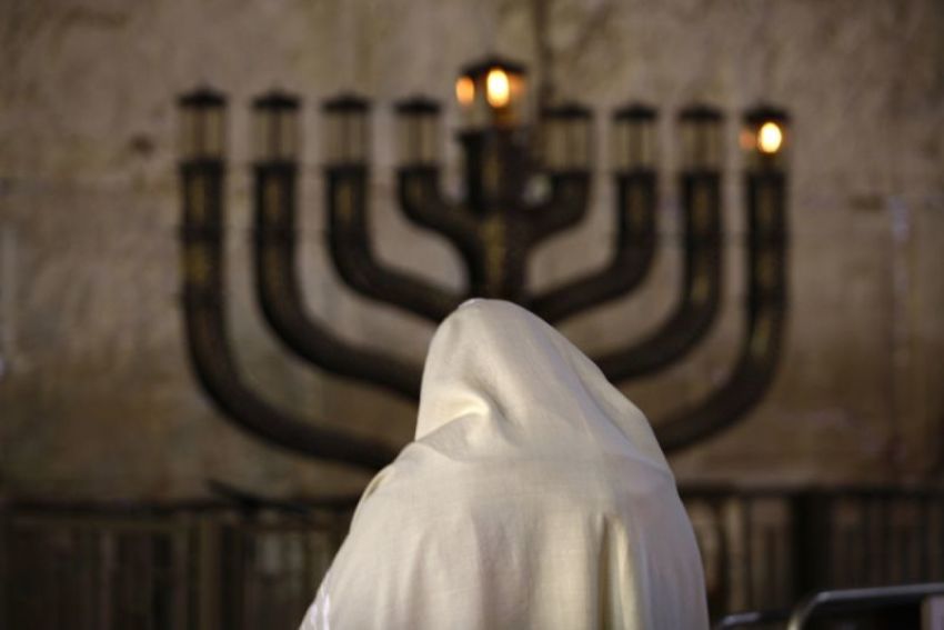 A Jewish man prays in front Menorah candles on the first night of the Jewish festival of Hanukkah at the Western Wall in Jerusalem's Old City December 21, 2008. Hanukkah, which means