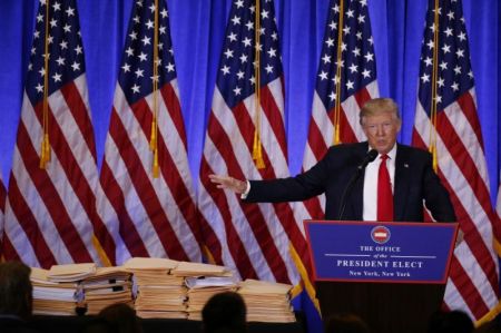 Then President-elect Donald Trump gestures to documents that allegedly transferred "complete and total control" of his businesses while he speaks at a news conference in the lobby of Trump Tower in NYC on Jan. 11, 2017.