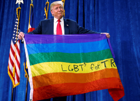 Donald Trump holds up a rainbow flag with "LGBTs for TRUMP" written on it at a campaign rally in Greeley, Colorado, October 2016.