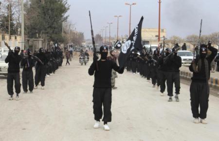 ISIS fighters carry their weapons as they parade along a street in an occupied territory in Syria.