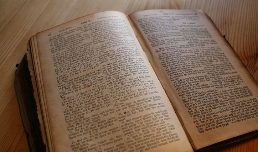 An ancient BIble lies open on a table.