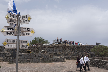 Ultra Orthodox Jews and tourists gather next to signs pointing out distances to different cities on Mount Bental next to the Syrian border in the Israeli-annexed Golan Heights on May 10, 2018.