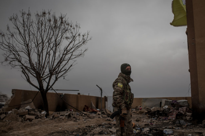 A Syrian Democratic Forces soldier fighterstands in the courtyard of a building at a position in the final ISIL encampment Baghouz, Syria, on March 24, 2019.