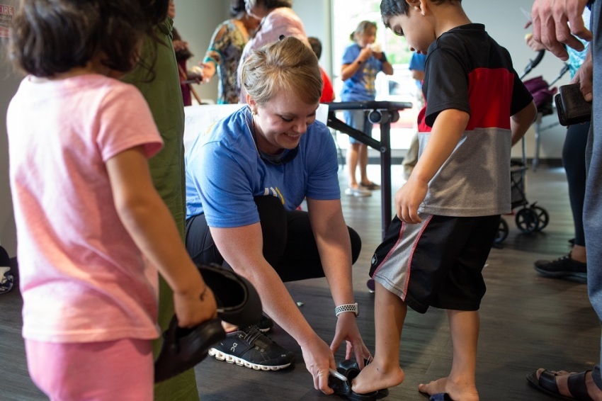 A Send Relief volunteer helps a child put on shoes he was given at the "Back to School Party" held at the Send Relief Ministry Center in Clarkston, Georgia on Aug. 3. 2019.