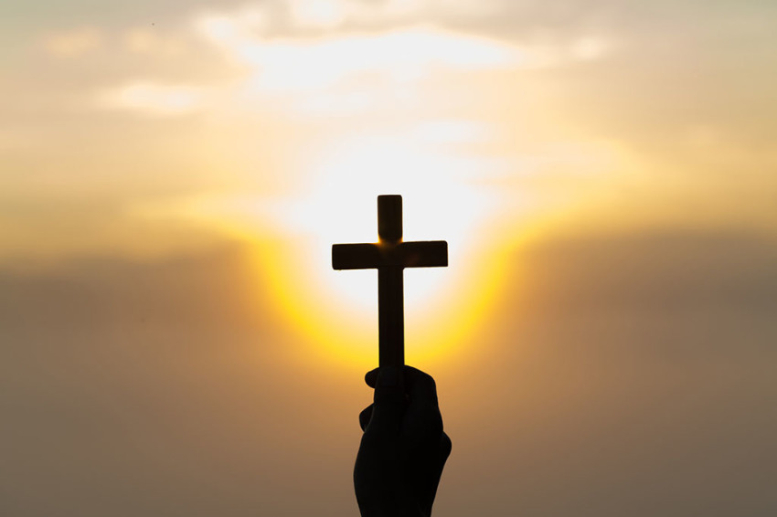 Silhouette of a cross against the sky during sunset.