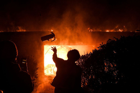 A protester throws a fire extinguisher in a burning building during a demonstration in Minneapolis, Minnesota, on May 29, 2020. Violent protests erupted across the United States late on May 29 over the death of a handcuffed black man in police custody, with murder charges laid against the arresting Minneapolis officer failing to quell seething anger.