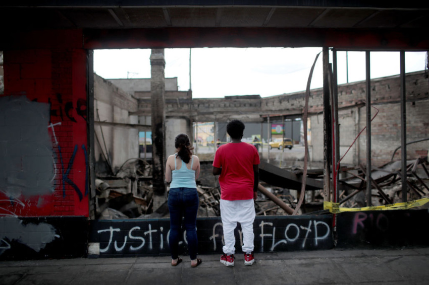 People look at the charred wreckage of a building destroyed during last week's rioting sparked by the death of George Floyd on Memorial Day in Minneapolis, Minnesota, on June 2, 2020.