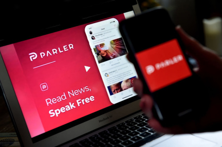 This illustration picture shows social media application logo from Parler displayed on a smartphone with its website in the background in Arlington, Virginia, on July 2, 2020. Amid rising turmoil in social media, Parler is gaining with prominent political conservatives who say their voices are being silenced by Silicon Valley giants. Parler, founded in Nevada in 2018, bills itself as an alternative to "ideological suppression" at other social networks.