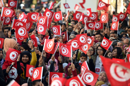 Tunisians wave national flags and shout slogans on Jan. 14, 2016, during a rally on Habib Bourguiba Avenue in Tunis to mark the fifth anniversary of the 2011 revolution.