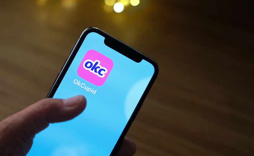 This illustration shows a person looking at the OkCupid dating app on a smartphone in Los Angeles, on February 11, 2021. Dating apps offer a snapshot about a person's life, but in the space of a few weeks, a surprising health issue has emerged as a dealmaker or heartbreaker: have you had the coronavirus vaccine? Some are bragging they have gotten the shot in order to better their chances, while others are using it to justify what one singleton described as 