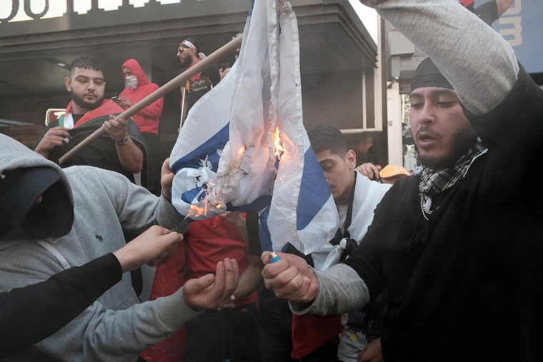 Pro Palestinian protesters burn the Israeli flag as they face off with a group of Israel supporters and police in a violent clash in Times Square on May 20, 2021, in New York City. Despite an announcement of a cease fire between Israel and Gaza militants, dozens of supporters of both sides of the conflict fought in the streets of Times Square. Dozens were arrested and detained by police before they were dispersed out of the square. | Spencer Platt/Getty Images