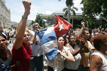 Cuban government's supporters wave flags and chant slogans as they harass a demonstration of dissidents on July 13, 2005, in Havana. Apparently, the dissidents intended to make a protest march to commemorate the 11th anniversary of the sinking by the Cuban Navy of the tug