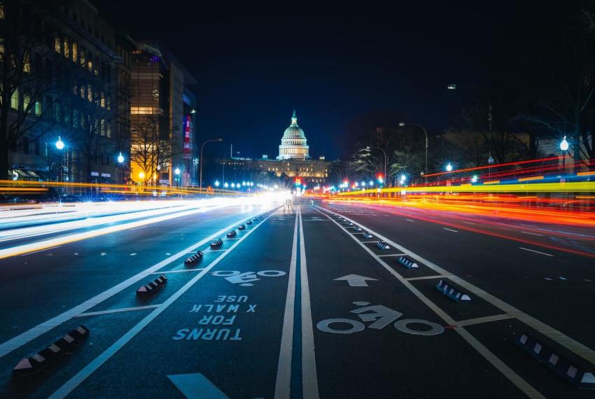 Cars drive in Washington, D.C. with the U.S. Capitol in the background.