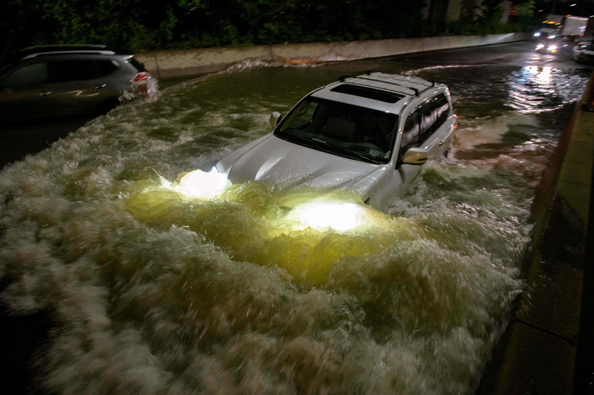 A motorist drives a car through a flooded expressway in Brooklyn, New York early on September 2, 2021, as flash flooding and record-breaking rainfall brought by the remnants of Storm Ida swept through the area.