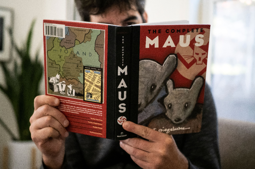 This illustration photo taken in Los Angeles, California on January 27, 2022, shows a person holding the graphic novel "Maus" by Art Spiegelman. 