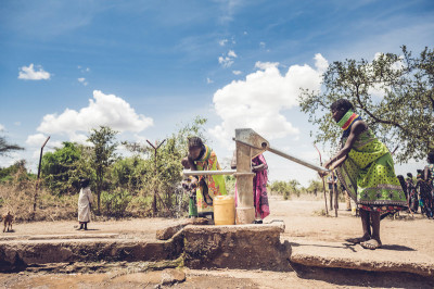 Two women in Kenya stand at a pump to obtain water in Turkana County, Kenya.