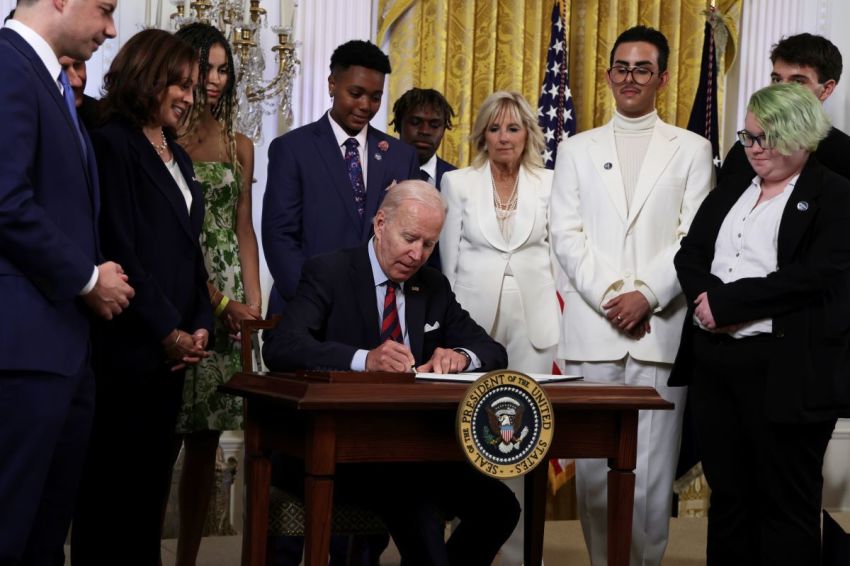 President Joe Biden signs an executive order on advancing equality for LGBT individuals as Transportation Secretary Pete Buttigieg (L), Vice President Kamala Harris (2nd L), first lady Jill Biden (3rd R) and Javier Gomez (2nd R) of Florida and other LGBT advocates look on during a pride event at the East Room of the White House on June 15, 2022 in Washington, D.C.