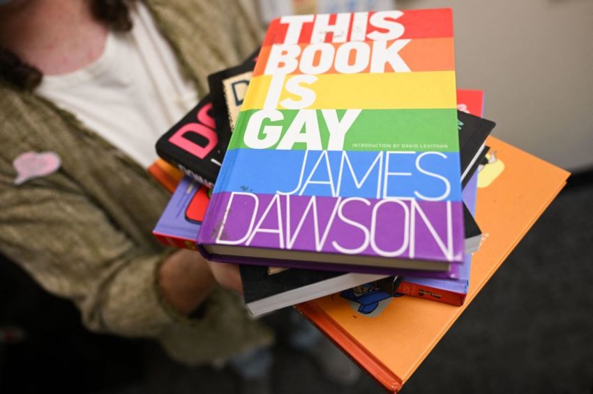 Laramie Pridefest board member Tyler Wolfgang displays a stack of books, some of which have been banned across the U.S. due to controversy, including "This Book is Gay," in their office on the University of Wyoming campus in Laramie, Wyoming, on August 13, 2022.