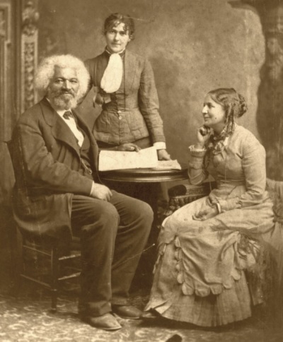 A family photo of Frederick Douglass and his second wife, Helen Pitts Douglass. Standing in the background is Helen's sister, Eva Pitts.