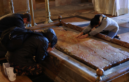 Worshipers kneel down around the Stone of Anointing, the place believed to be where Jesus Christ's body was laid after being taken down from the cross, during an Easter vigil mass on Holy Saturday at the Church of the Holy Sepulchre in Jerusalem, on April 3, 2021.