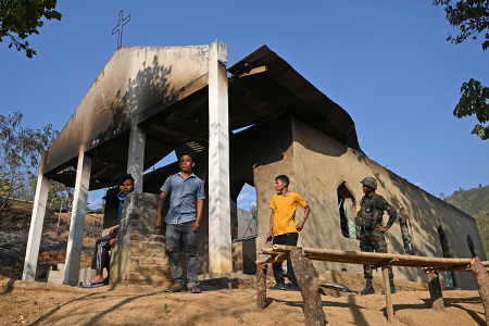 An Indian army soldier (R) stands along with villagers in front of a ransacked church that was set on fire by a mob in the ethnic violence hit area of Heiroklian village in Senapati district, in India's Manipur state on May 8, 2023. Around 23,000 people have fled the unrest which erupted last week in the hilly northeast state bordering Myanmar. The latest clashes erupted between the majority Meitei people, who are mostly Hindu, living in and around the Manipur capital Imphal and the mainly Christian Kuki tribe of the hills.