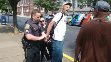 A police officer takes street preacher Damon Atkins into custody during a pride event in Reading, Penn.