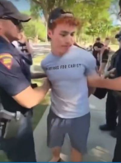 A screenshot of a video showing a Christian street preacher arrested at a Wisconsin drag event.