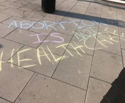 Chalk writing stating "Abortion Is Not Healthcare" is seen near the Elijah Barrett Prettyman U.S. Courthouse in Washington, D.C., August 9, 2023, 