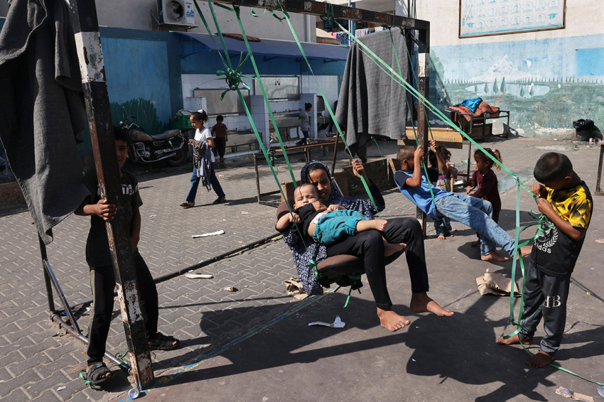 Children play on a swing in the playground of a school run by the United Nations Relief and Works Agency for Palestine Refugees (UNRWA), that has been converted into a shelter for displaced Palestinians in Rafah in the southern Gaza Strip on October 25, 2023, amid ongoing battles between Israel and the Palestinian group Hamas.