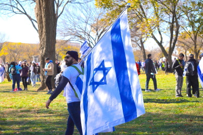 A demonstrator at the Americans March for Israel event carries an Israeli flag alongside other demonstrators in support of the effort to combat antisemitism and show support for Israel's war against Hamas in Washington, D.C., on November 14, 2023.