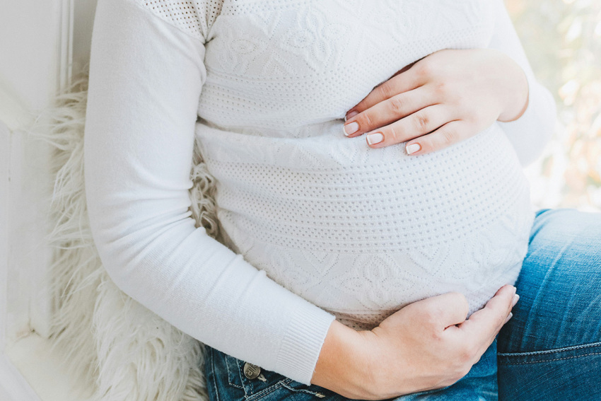 A pregnant woman holds her belly.