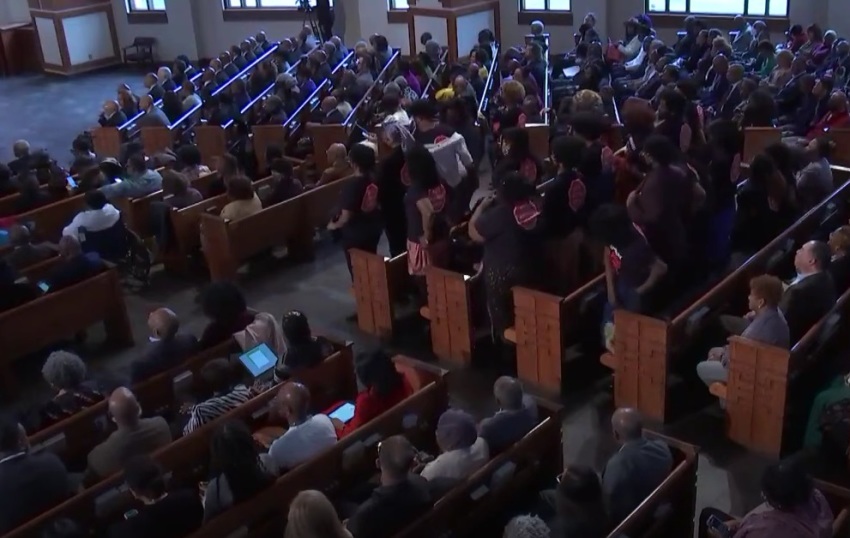 A group of students stand in protest while Sen. Raphael Warnock, D-Ga., preaches a sermon at Ebenezer Baptist Church of Atlanta, Georgia, on Sunday, March 3, 2024.