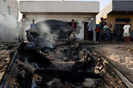 Palestinians stand around a charred fishing boat that was hit by an Israeli airsrike on the Mediterranean coast of Rafah in the southern Gaza Strip on May 22, 2024, amid the ongoing conflict between Israel and the Palestinian Hamas group.