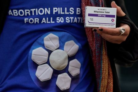 A pro-abortion rights activist holds a box of mifepristone during a rally in front of the US Supreme Court on March 26, 2024, in Washington, DC.