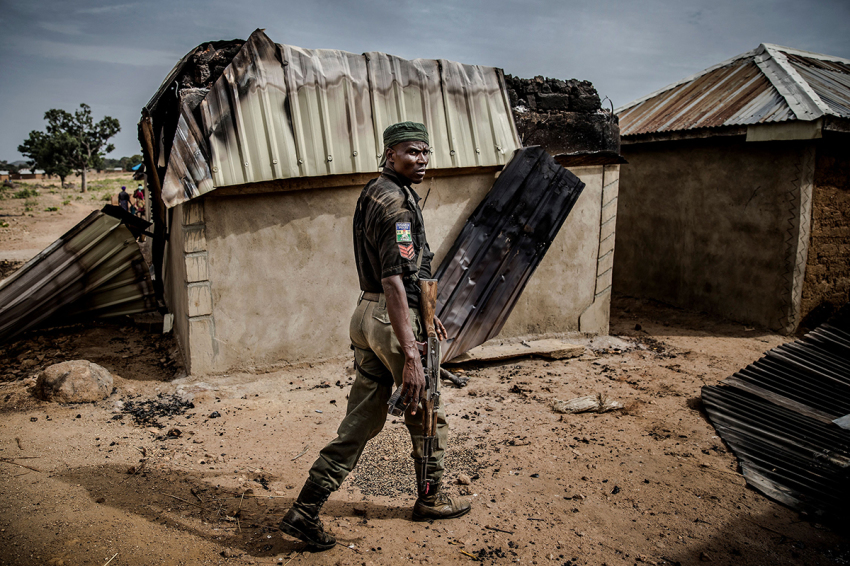 A Nigerian police officer patrols an area of destroyed and burned houses after a Fulani attack in the Adara farmers' village of Angwan Aku, Kaduna State, Nigeria, on April 14, 2019.