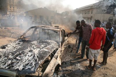 Men look at the wreckage of a car following a bomb blast at St. Theresa Catholic Church outside the Nigerian capital Abuja on December 25, 2011. Two explosions near churches during Christmas Day services in Nigeria, including one outside the country's capital, killed at least 28 people amid spiralling violence blamed on an Islamist group.