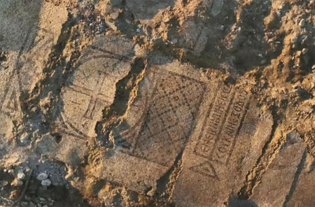 The mosaic, featuring a cross and an inscription at its center.