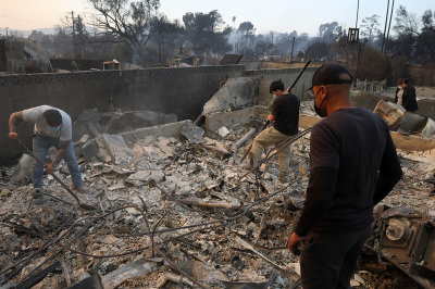 Residents dig through the remains of their family's home that was destroyed by the Eaton Fire on Jan. 09, 2025, in Altadena, California. Fueled by intense Santa Ana winds, the Eaton Fire has grown to over 10,000 acres and has destroyed many homes and businesses.