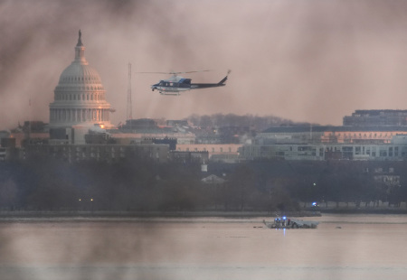 A helicopter flies near the crash site of the American Airlines plane on the Potomac River after the plane crashed on approach to Reagan National Airport on Jan. 30, 2025, in Arlington, Virginia. The American Airlines flight from Wichita, Kansas, collided with a military helicopter while approaching Ronald Reagan National Airport. Dozens of people are feared to have died in the midair collision. (Photo by Andrew Harnik/Getty Images)