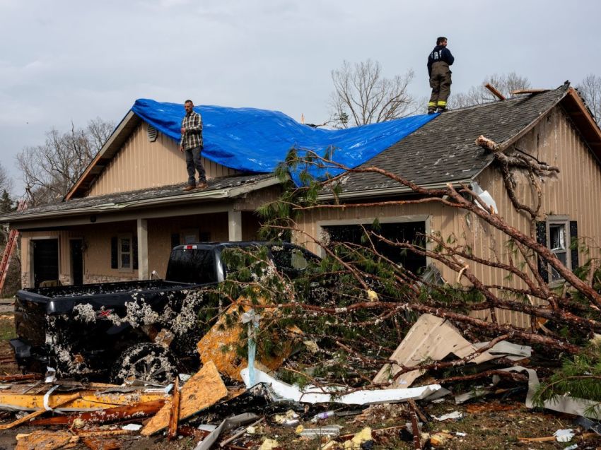 People help cover a damaged roof on March 15, 2025 in Poplar Bluff, Missouri. Many homes throughout Harmony Hills were damaged by the severe weather on Friday night that left one person dead in Butler County, Missouri. At least 19 people have reportedly been killed after tornadoes and severe storms hit several midwest and southern states overnight.