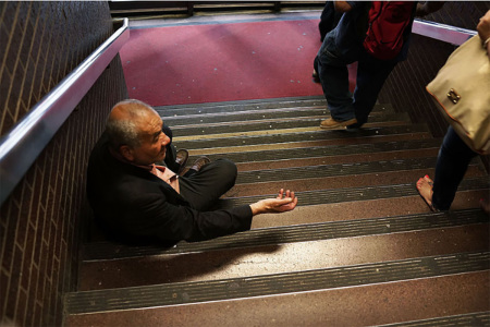 A man begs for money on a staircase at the entrance to the Port Authority Bus Terminal in New York.