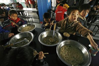 Young residents eat their lunch at the Sun Village foster home in the village of Banqiao on the outskirts of Beijing, 31 March 2007. The Sun Village foster home is a non-governmental organization established by former policewoman Zhang Shuqin ten years ago to foster and educate the underage children of Chinese prisoners. The village is home to over 100 children aged between one and eighteen, with some children having witnessed one parent killing the other and some being abandoned after either parent was imprisoned while others were abused by their relatives.