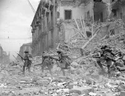 British soldiers scramble over rubble in a devastated street in Catania in August 1943 as part of the invasion of Sicily during World War II.