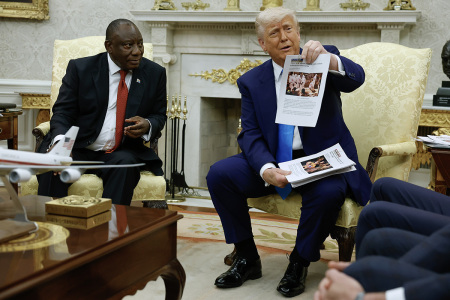 U.S. President Donald Trump holds up a printed article from "American Thinker" while accusing South Africa President Cyril Ramaphosa of state-sanctioned violence against white farmers in South Africa during a press availability in the Oval Office at the White House on May 21, 2025, in Washington, D.C.