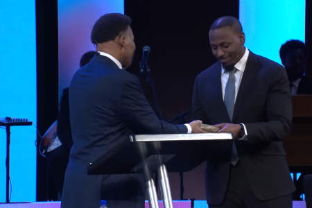 Tony Evans (L), founder of Oak Cliff Bible Fellowship Church in Dallas, Texas, gifts his father's Bible to his son, Jonathan Evans (R), during his official installation as the church's new lead pastor on Sunday Dec. 7. 2025.