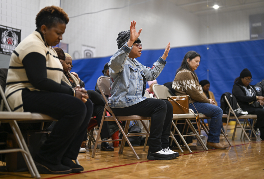 Sheletta Brundidge (C) holds up her hands during a prayer for the Somali community of Minnesota at the Brian Coyle Community Center on Dec. 4, 2025, in Minneapolis, Minnesota. The Trump administration has targeted the Somali immigrant community as ICE increased operations in Minnesota this week.