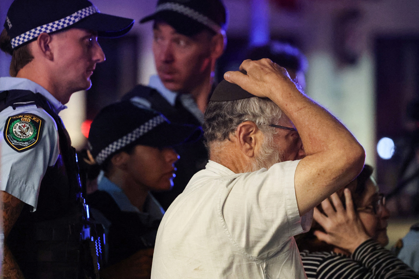 A member of the Jewish community reacts as he walks with police towards the scene of a shooting at Bondi Beach in Sydney on Dec. 14, 2025. Australian police said two people were in custody following reports of multiple gunshots on Dec.14 at Sydney's famed Bondi Beach, urging the public to take shelter.